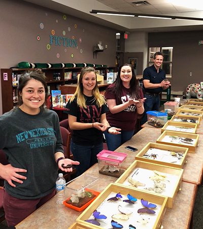 Students posing with insects at an outreach event